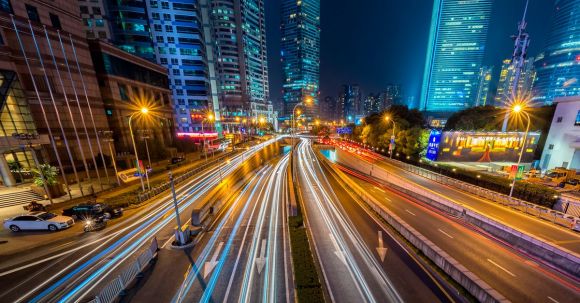 Smart Cities - Timelapse Photography of Vehicle on Concrete Road Near in High Rise Building during Nighttime