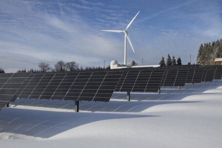 Renewable Energy - Solar Panels on Snow With Windmill Under Clear Day Sky